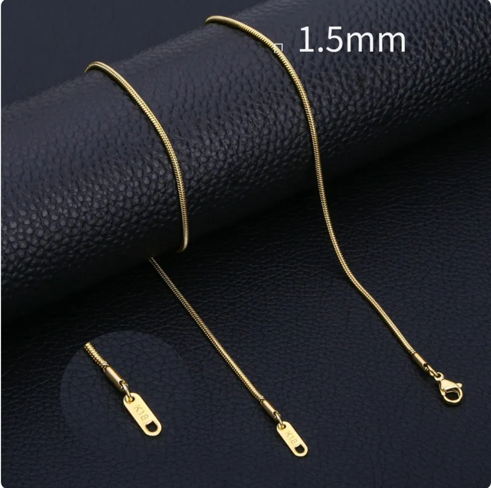 Minimalist stainless steel snake chain necklace in gold, showcasing smooth texture and elegance on leather background.