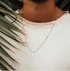 Model wearing a stainless steel clavicle chain necklace with a sleek pendant, enhancing casual style against tropical leaves.